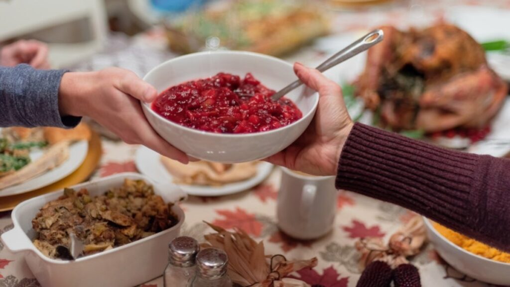 Hands passing a shared bowl of cranberry sauce across a holiday table, a common exposure during ERP for contamination OCD